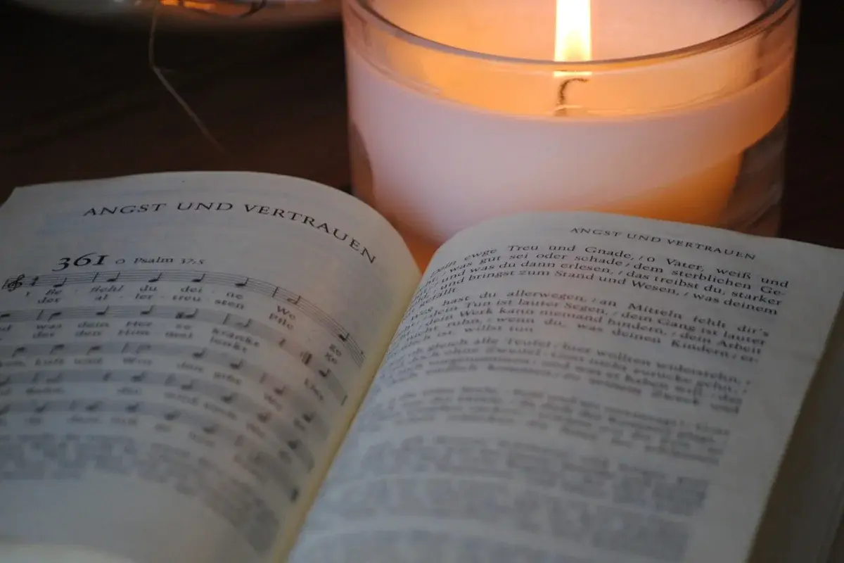 Aufgeschlagenes Evangelisches Gesangbuch mit Nummer 361; dahinter brennt eine weiße Kerze.