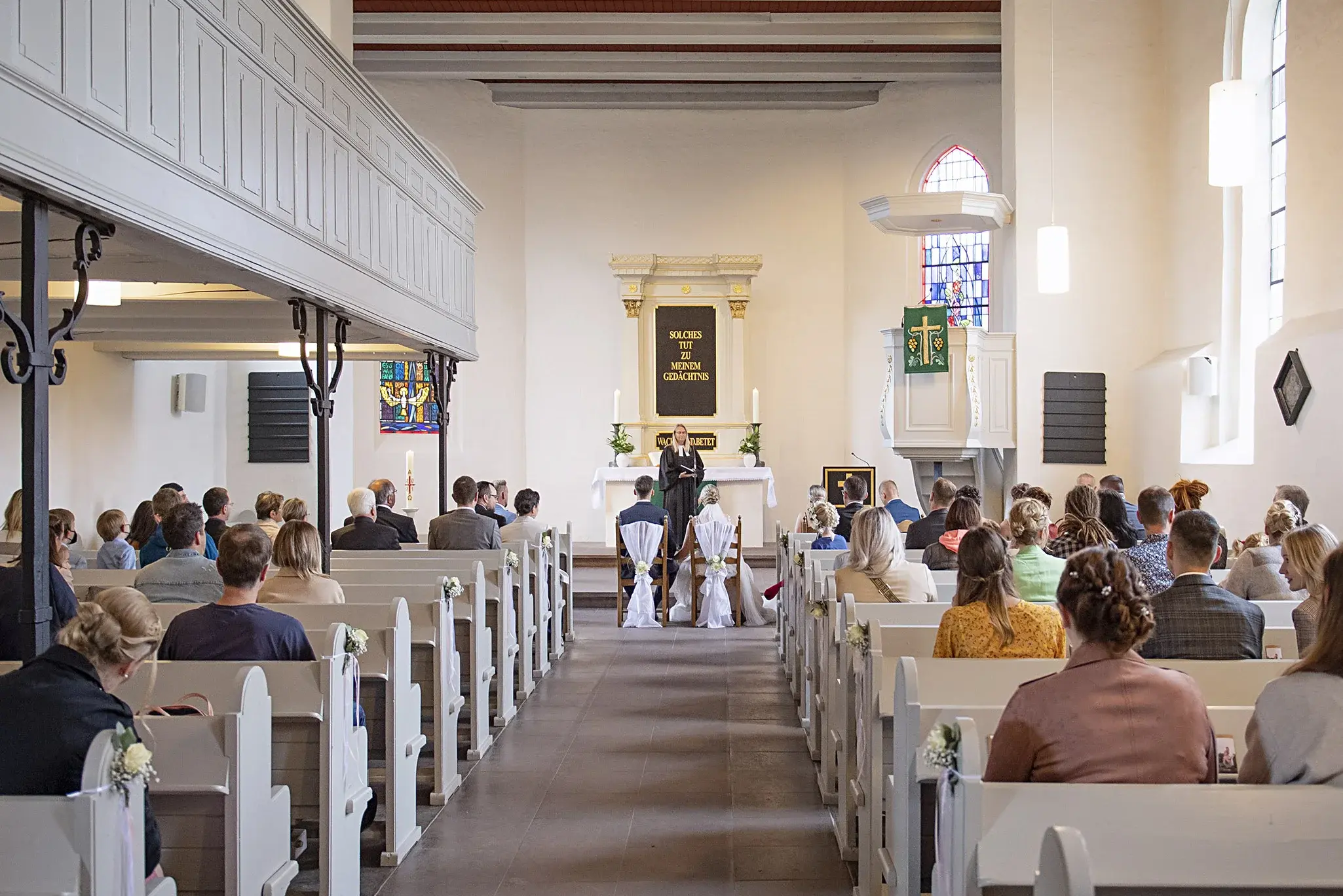 Der Blick geht von hinten nach vorne in der Marienkirche. Zu sehen ist ein Hochzeitspaar, das vor dem Altar sitzt. 