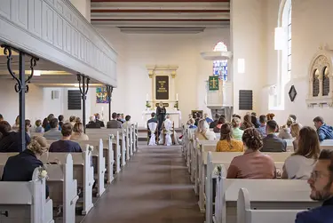 Der Blick geht von hinten nach vorne in der Marienkirche. Zu sehen ist ein Hochzeitspaar, das vor dem Altar sitzt. 